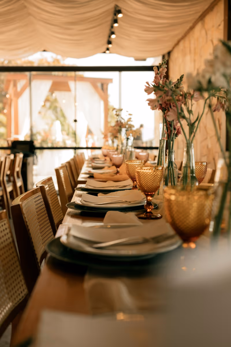 The back room laid for a private dinner, one long table set with amber glasses and low flowers